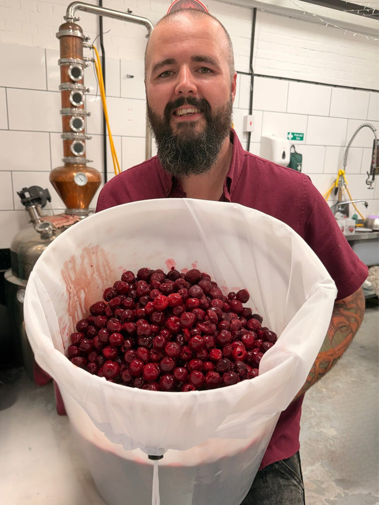 Tom holding a tub of Italian morello cherries in the distillery